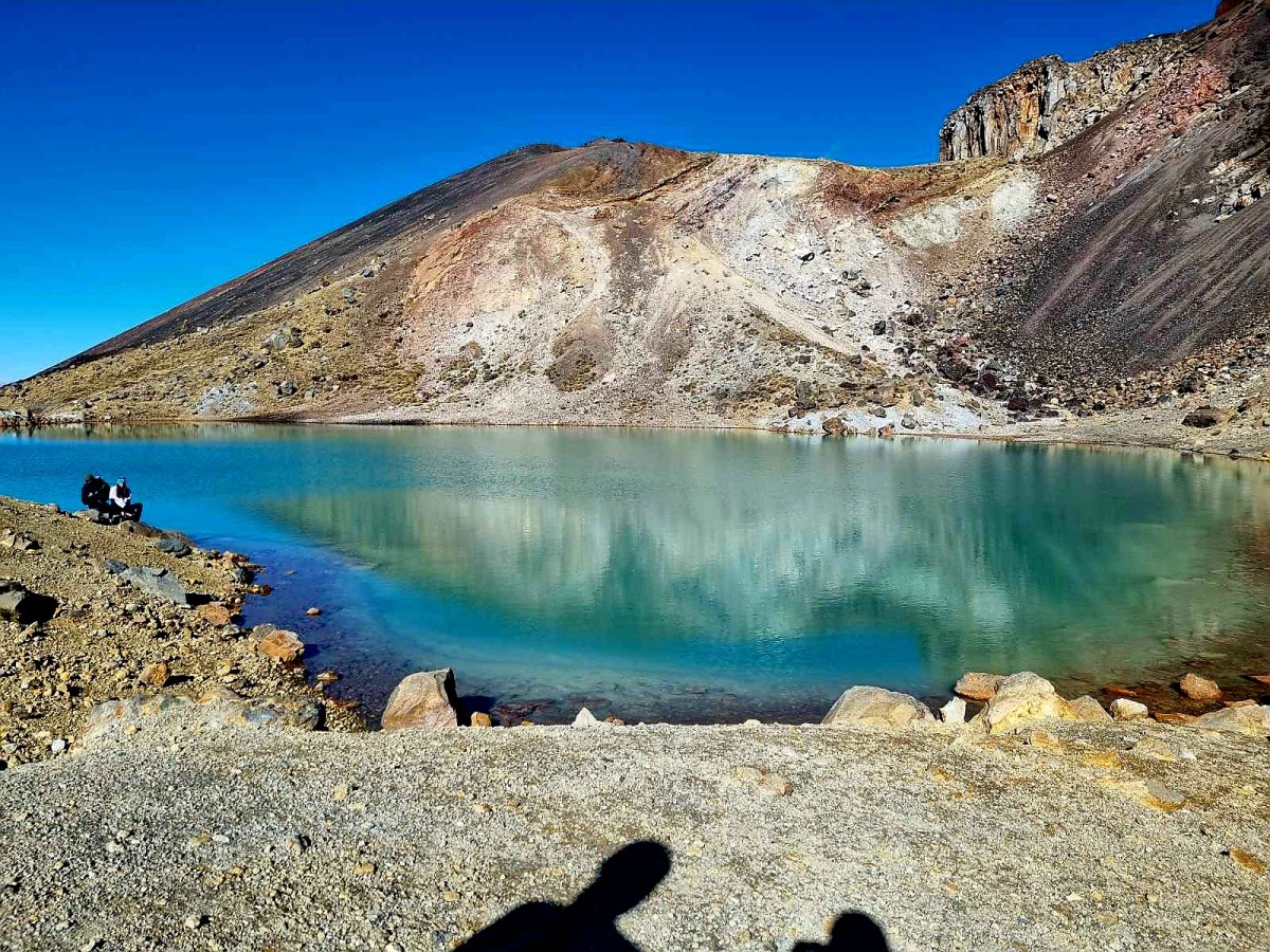 Turquoise lake with rocky mountain and clear blue sky.